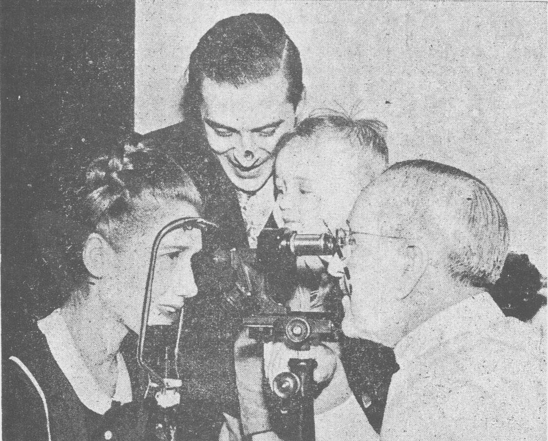 image/illustration region: a doctor examining a girl with the device while a woman and child watch